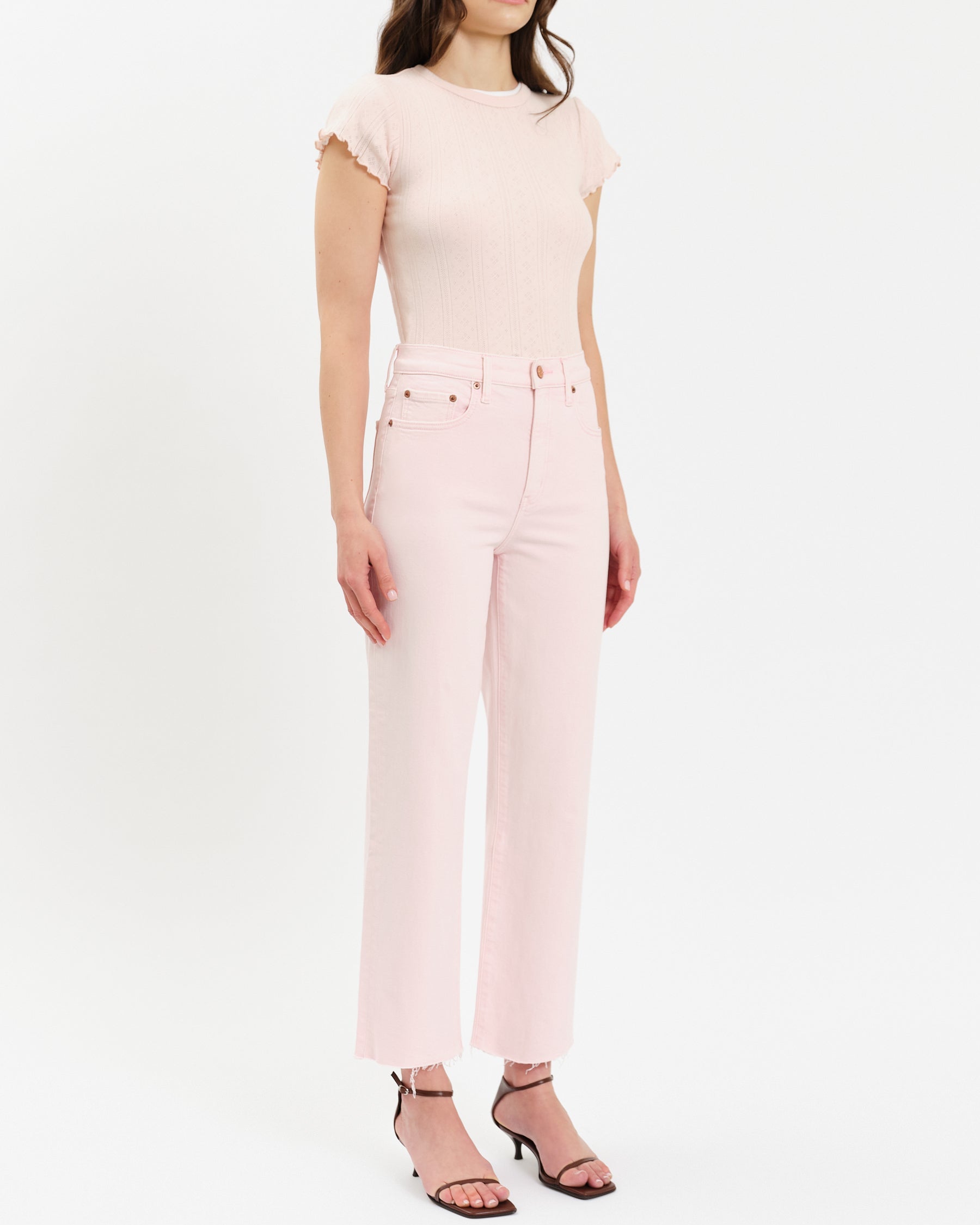 Woman wearing a light pink top and pants on a white background