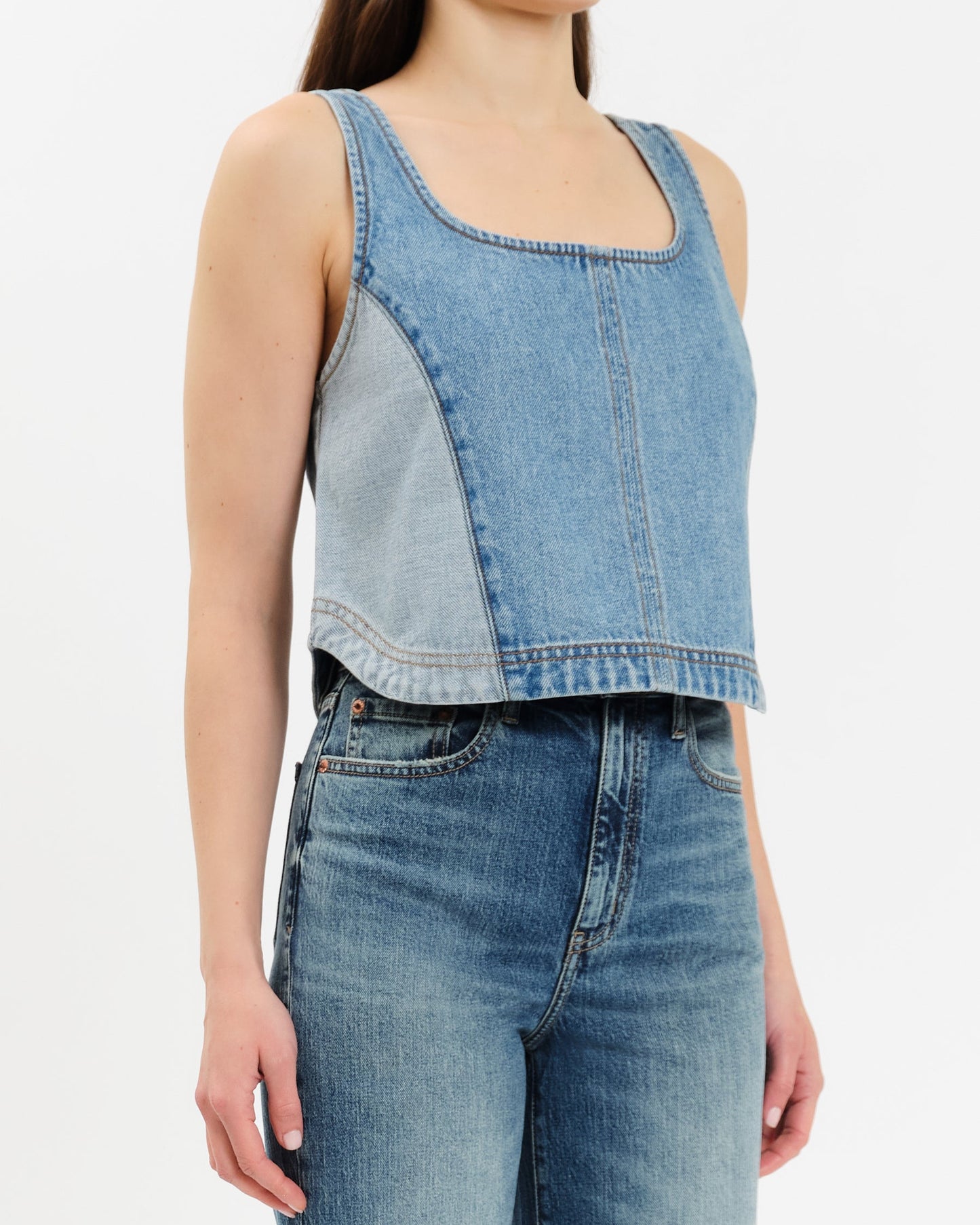 Denim sleeveless top and jeans on a plain background