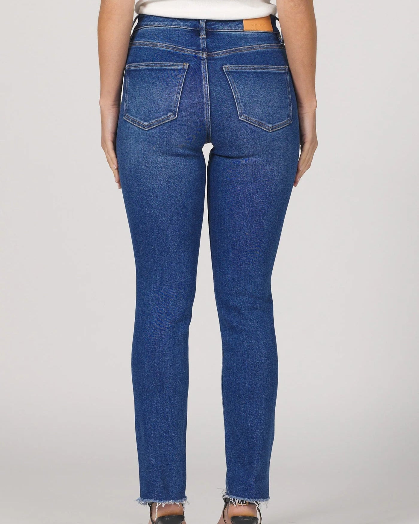 Person wearing blue jeans on a plain background