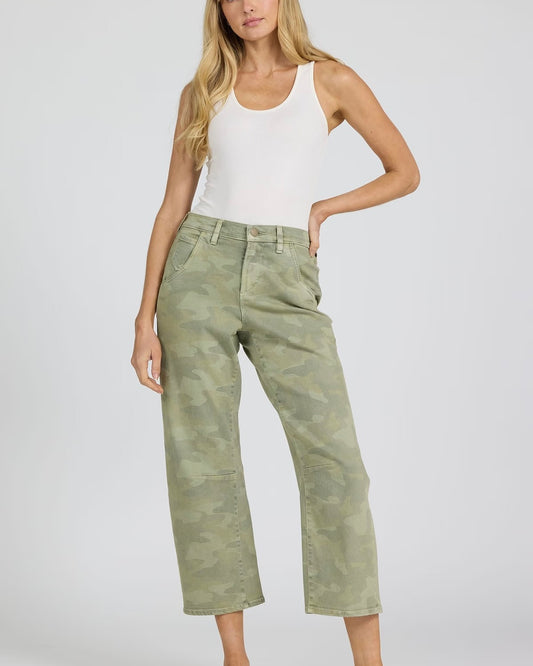 Woman wearing a white tank top and green camouflage pants on a plain background