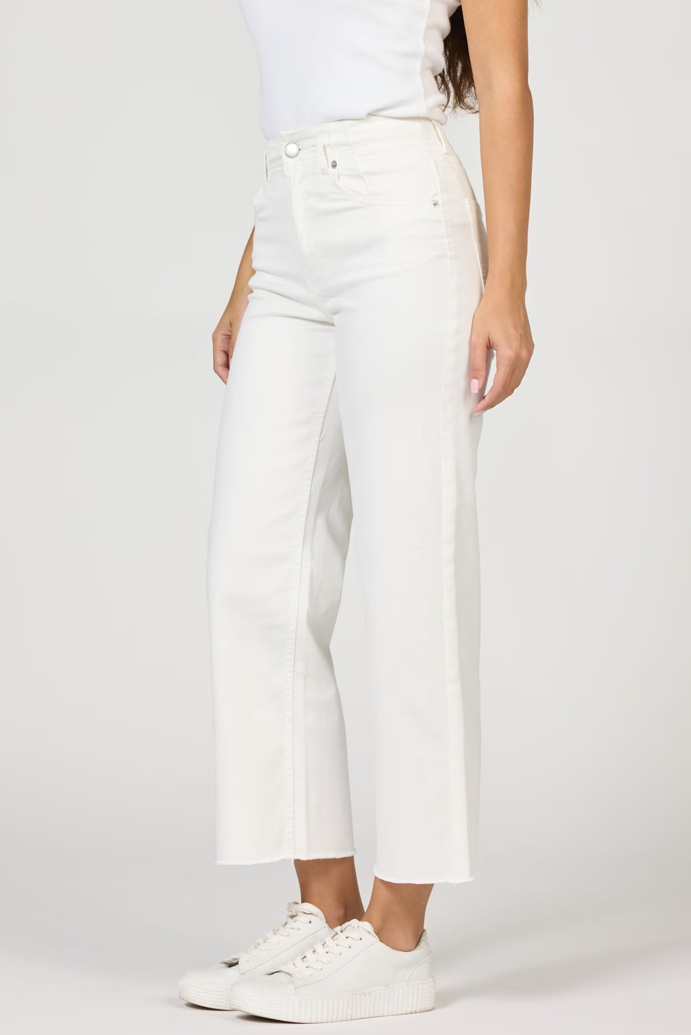 Person wearing white pants and white sneakers on a plain background