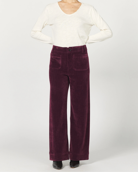 Woman wearing a white blouse and purple velvet pants on a white background