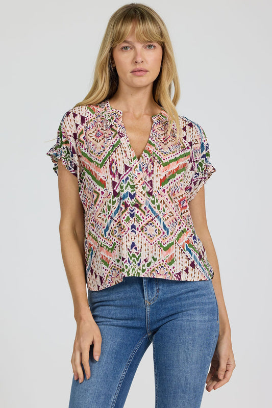 Woman wearing a colorful patterned blouse and blue jeans on a white background