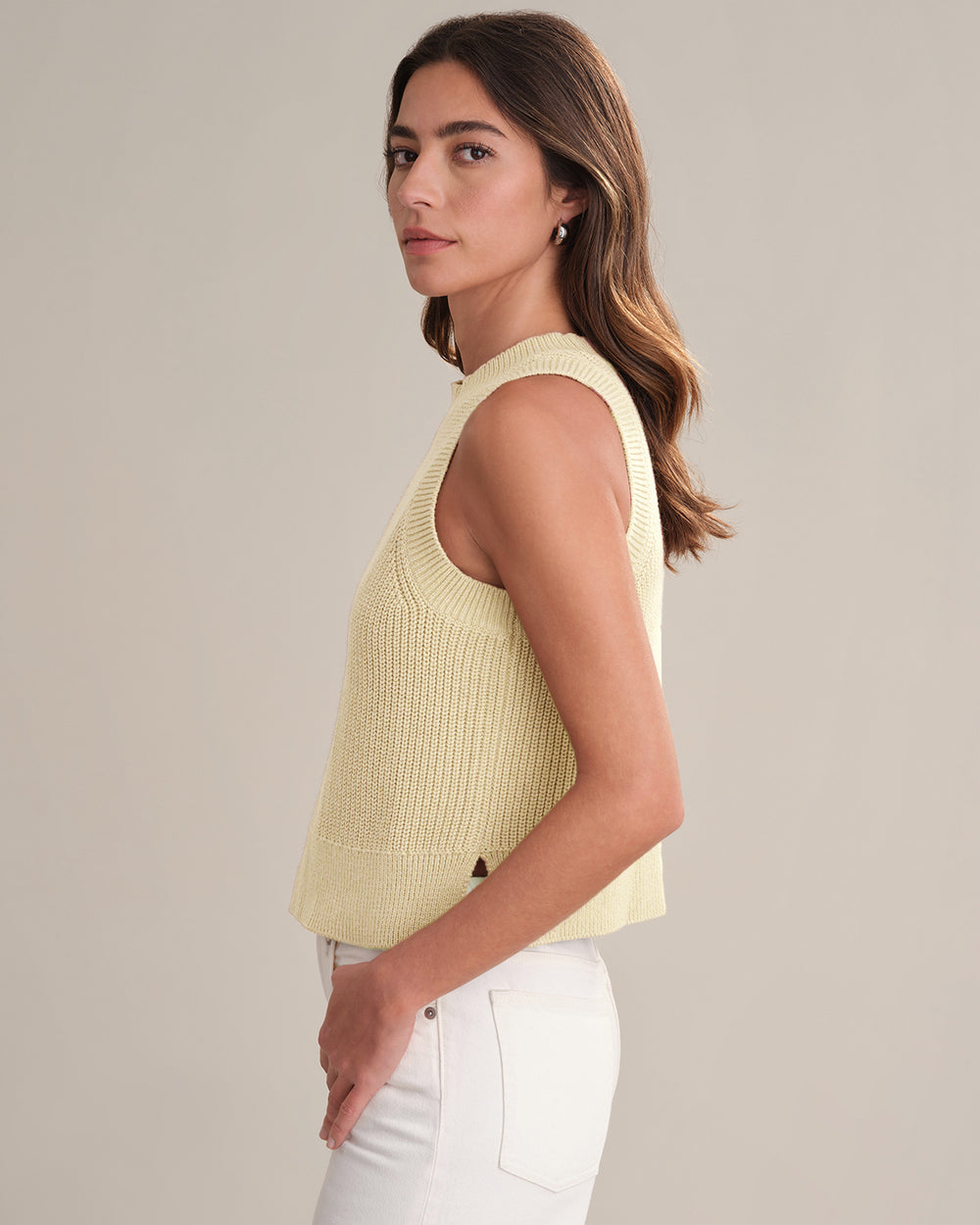 Woman wearing a light yellow sleeveless top against a neutral background