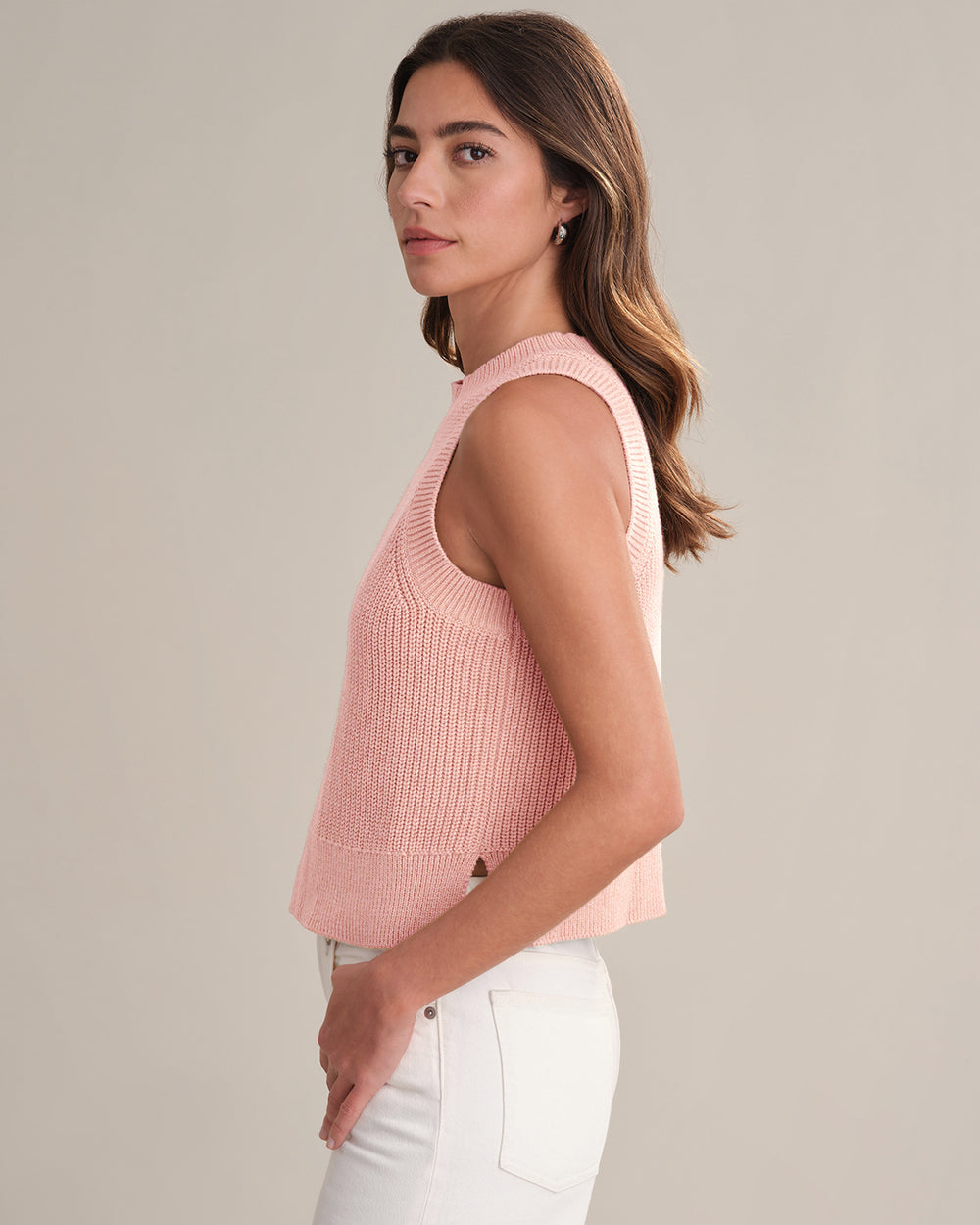 Woman wearing a pink sleeveless knitted top against a neutral background