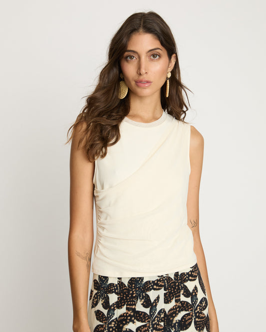 Woman wearing a sleeveless cream top and patterned skirt on a plain background