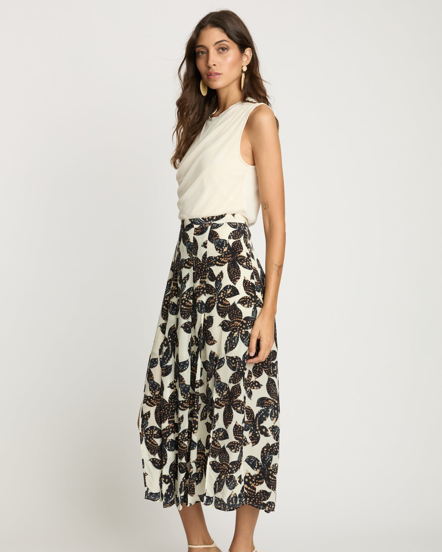Woman wearing a white sleeveless top and black floral skirt on a white background