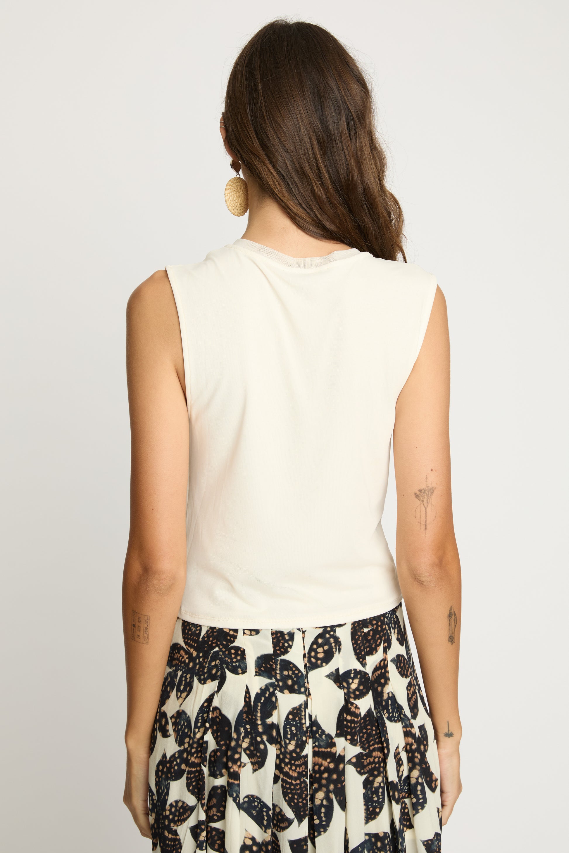 Woman wearing a sleeveless top and patterned skirt on a plain background