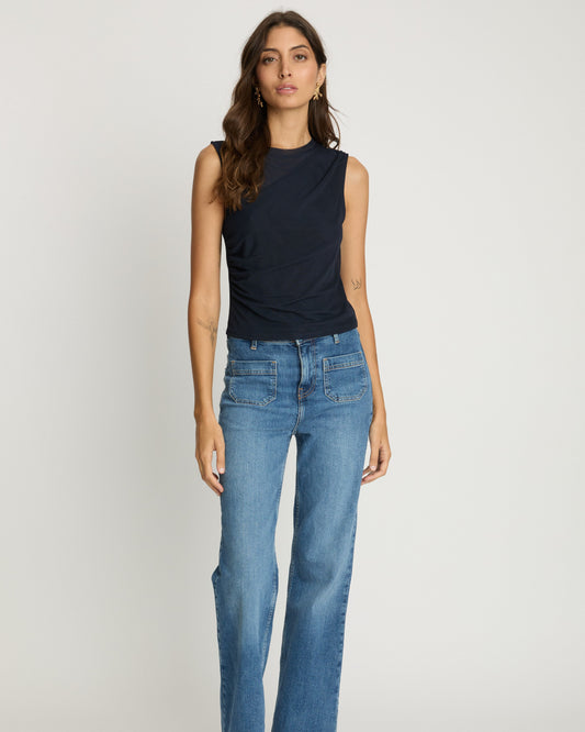Woman wearing a black sleeveless top and blue jeans on a white background