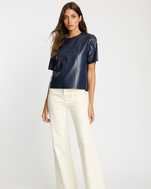 Woman wearing a navy blue top and white pants on a white background