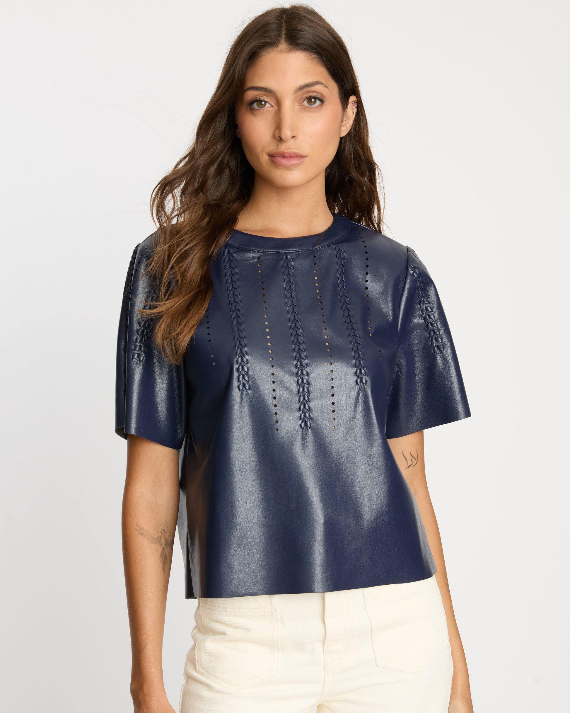 Woman wearing a navy blue leather top with cut-out details on a white background