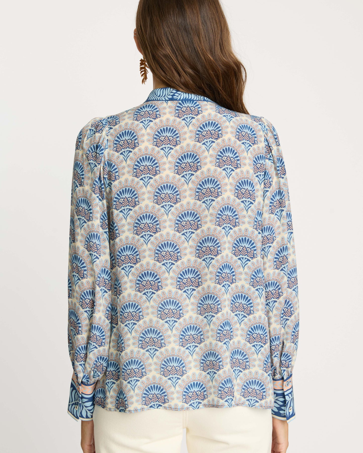 Woman wearing a blue and beige patterned blouse on a white background