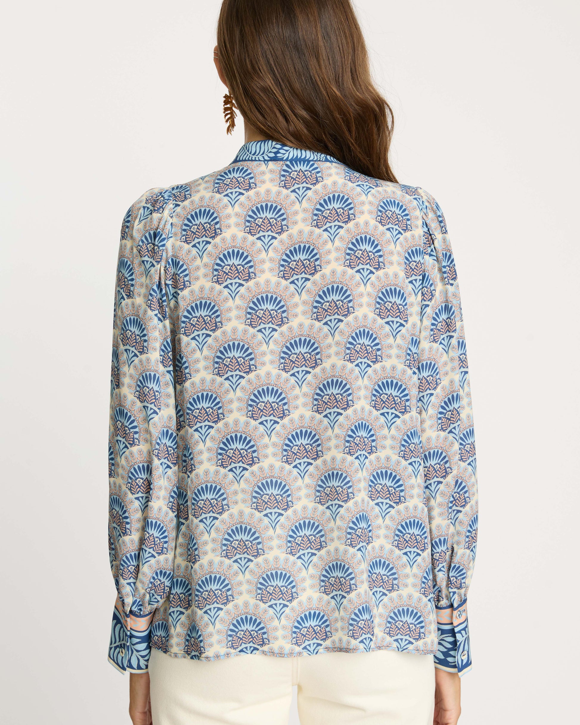 Woman wearing a blue and beige patterned blouse on a white background