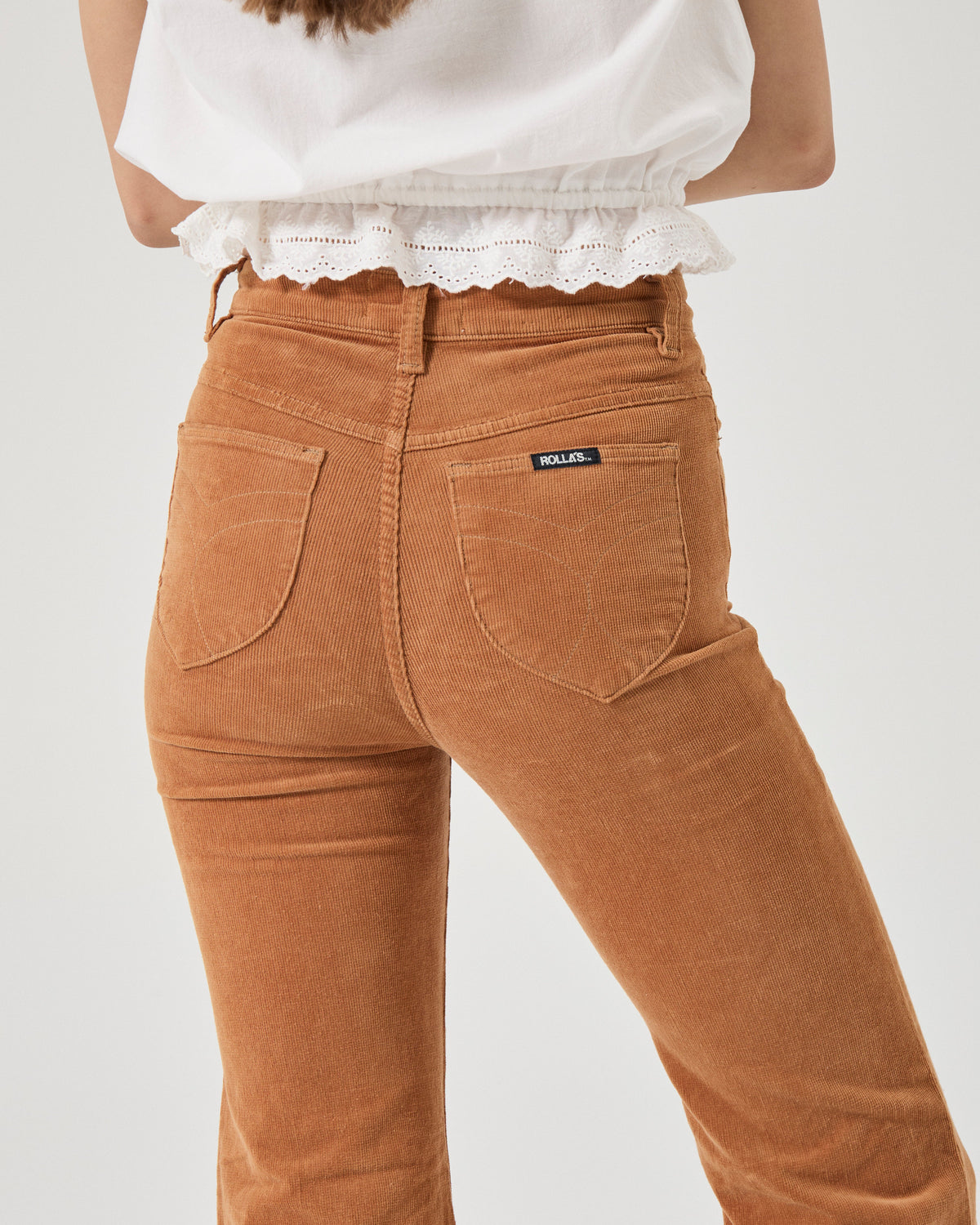 Brown corduroy pants worn by a person on a white background
