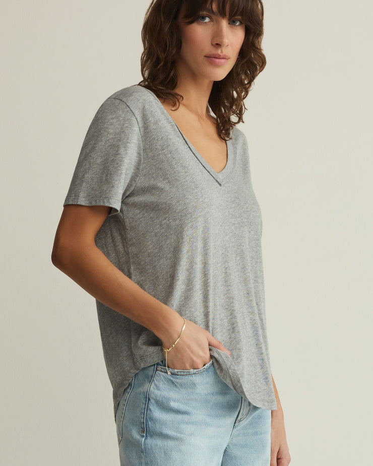 Woman wearing a gray t-shirt and light blue jeans on a plain background