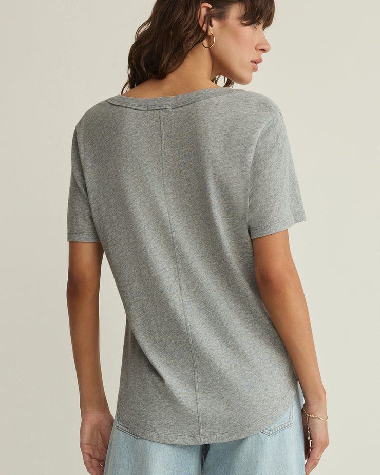 Woman wearing a gray t-shirt and light blue jeans on a beige background