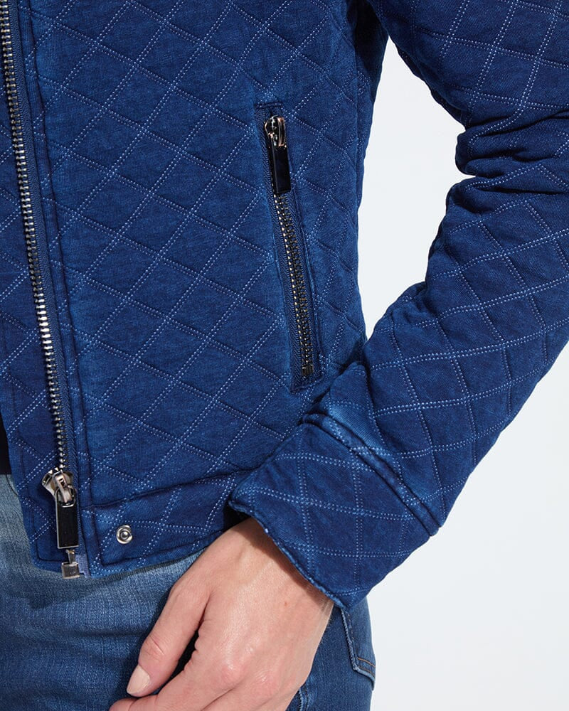 Blue quilted jacket with zippers on a light gray background