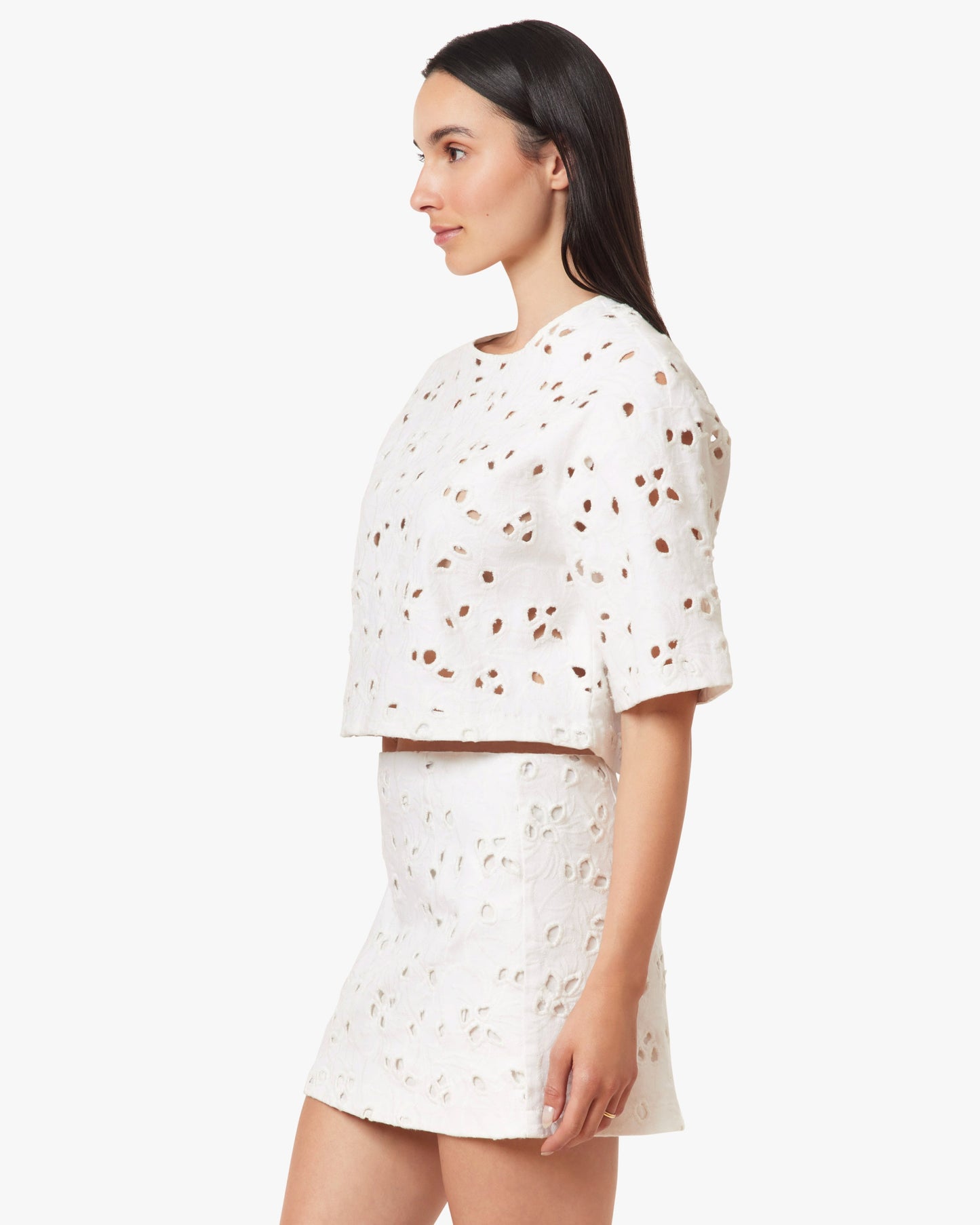 Woman wearing a white outfit with small patterns on a plain background