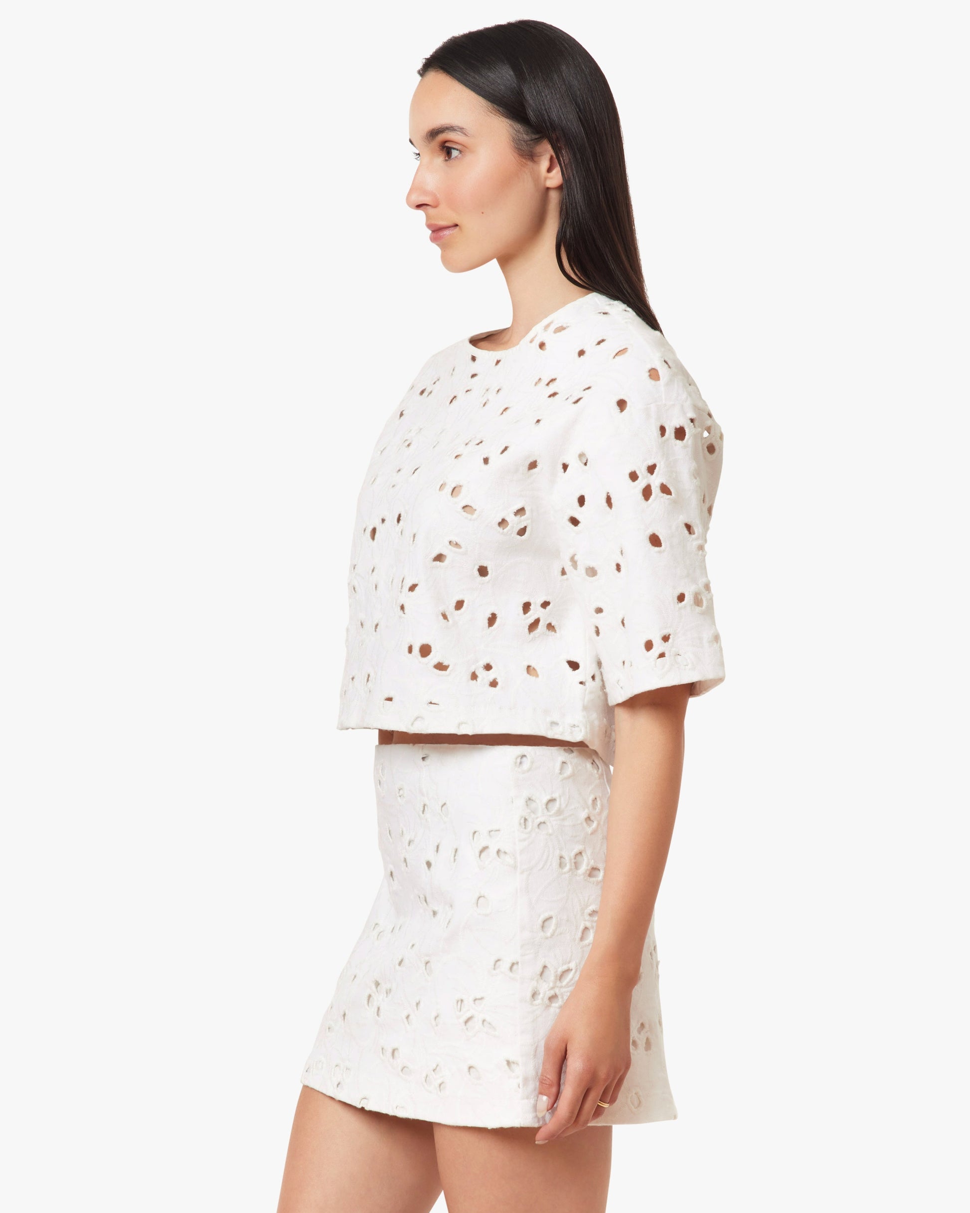 Woman wearing a white outfit with small patterns on a plain background