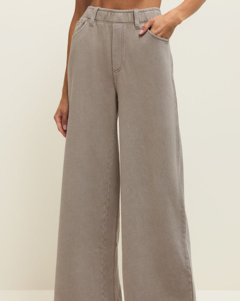 Person wearing light gray wide-leg pants with a plain background