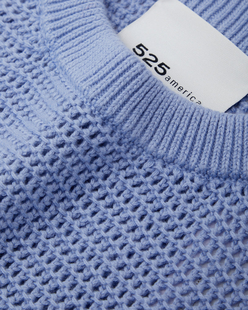 Close-up of a blue textured sweater with a white label displaying '525 America'.