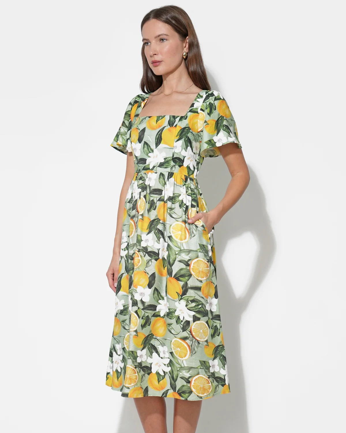 Woman wearing a dress with lemon and floral pattern on a white background