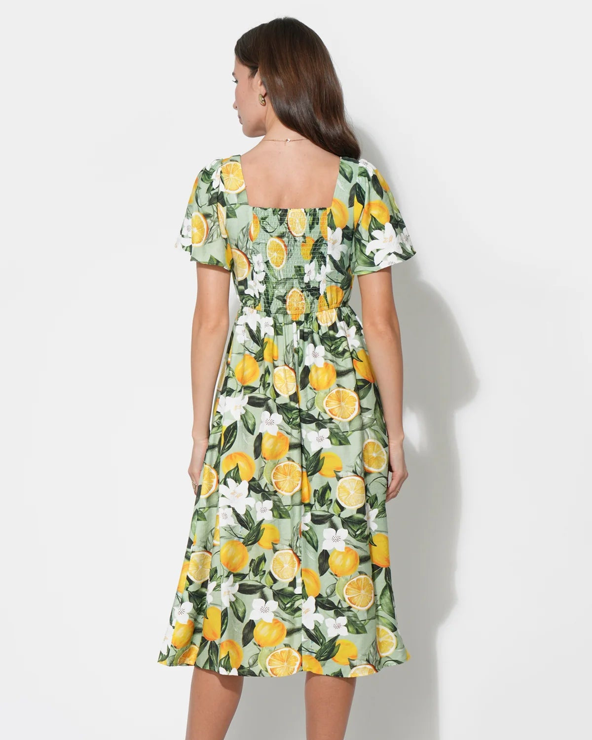 Woman wearing a floral dress with yellow flowers on a white background