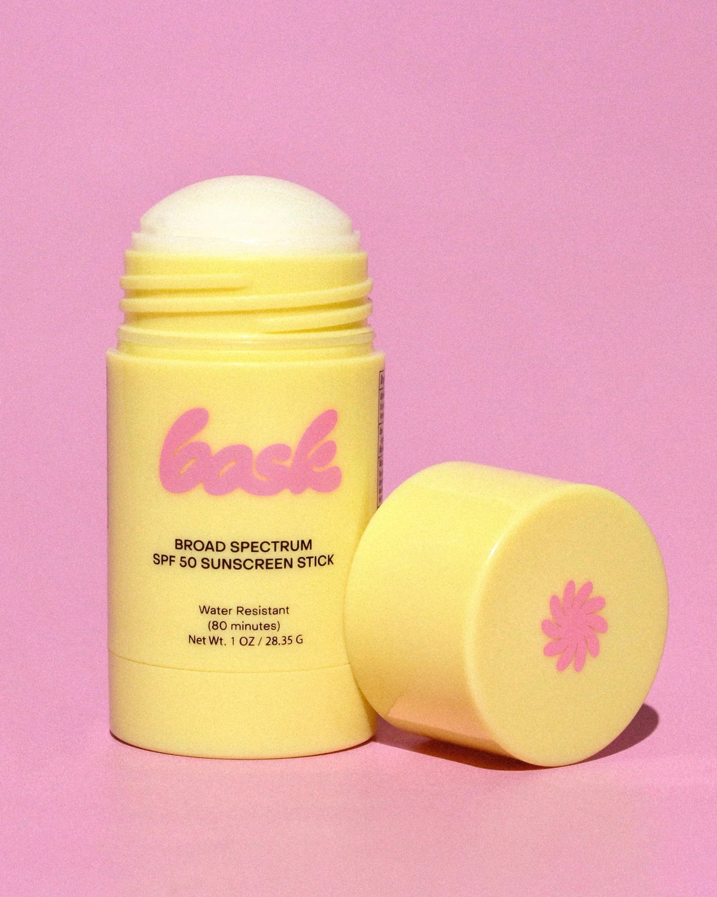 Yellow sunscreen stick with pink branding on a pink background
