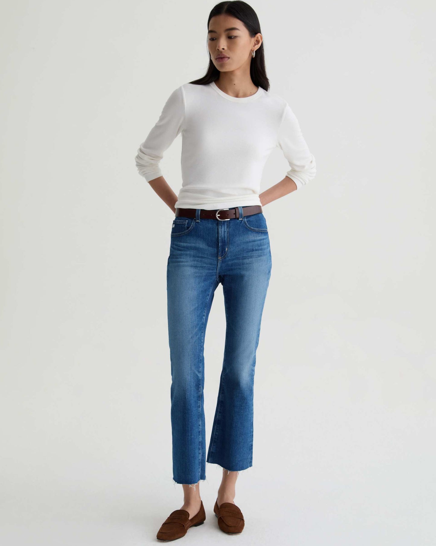 Woman wearing a white sweater and blue jeans on a white background
