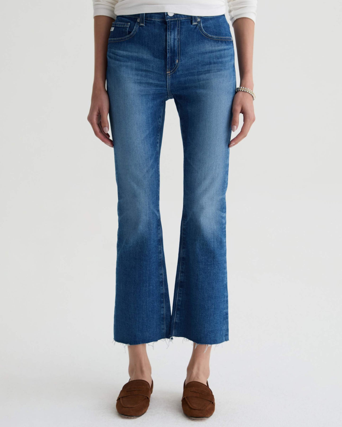 Person wearing blue flared jeans on a white background
