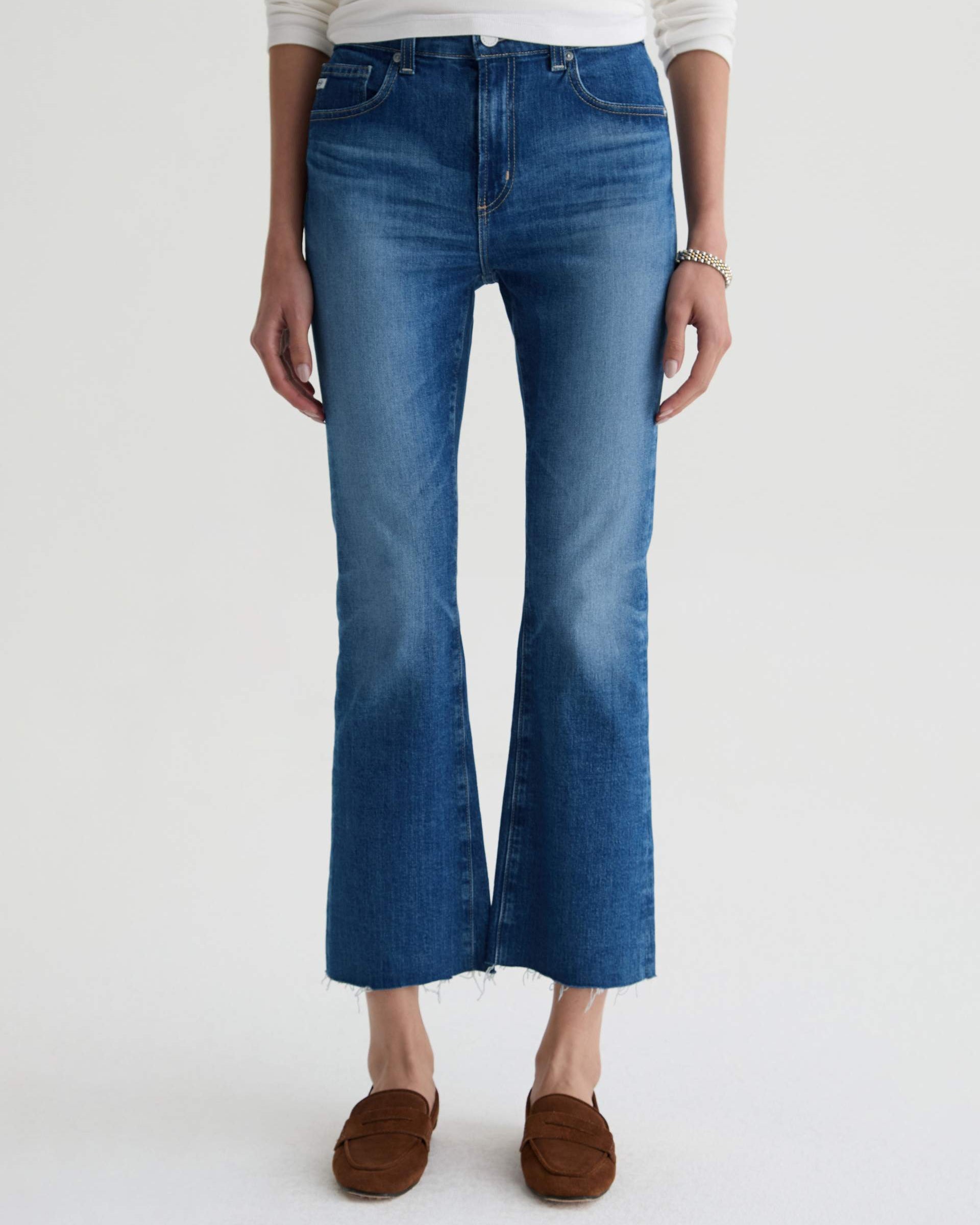 Person wearing blue flared jeans on a white background