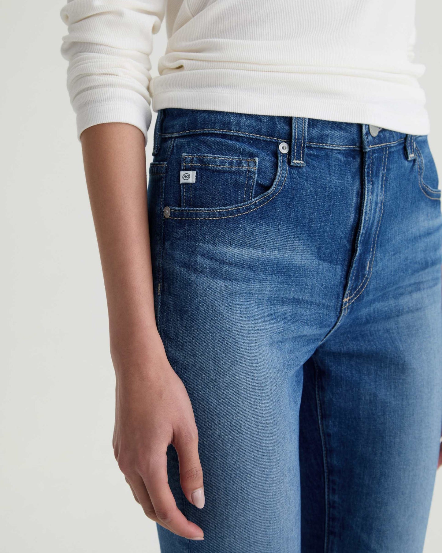 Blue jeans worn by a person on a plain background