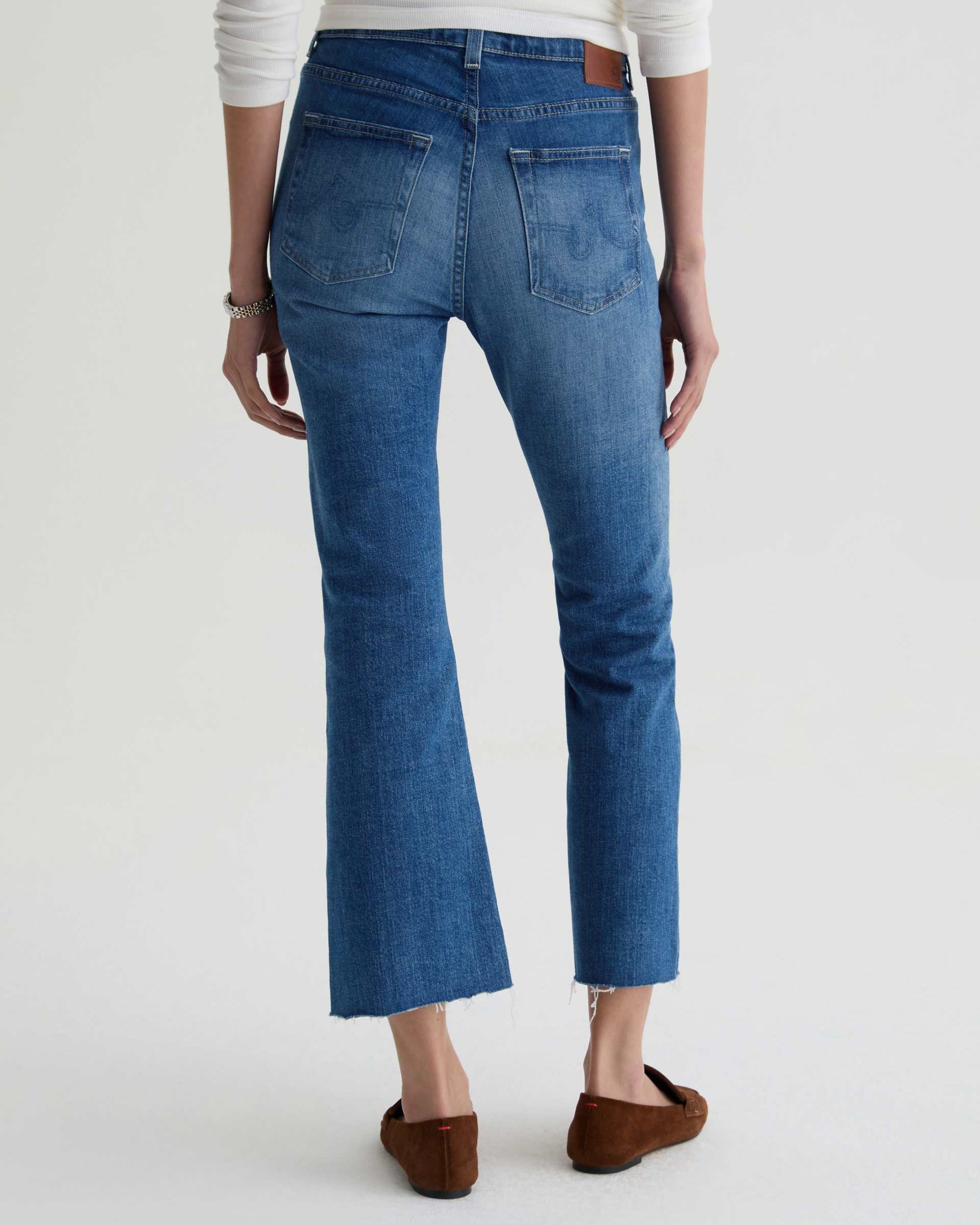 Person wearing blue jeans on a plain background