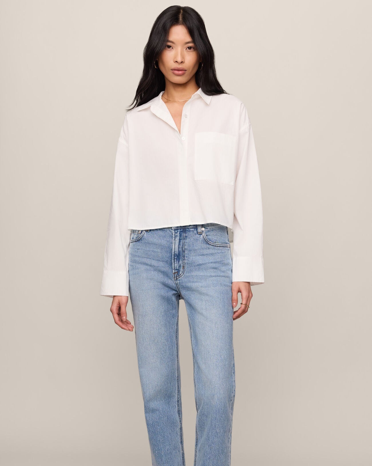 Woman wearing a white blouse and light blue jeans on a plain background