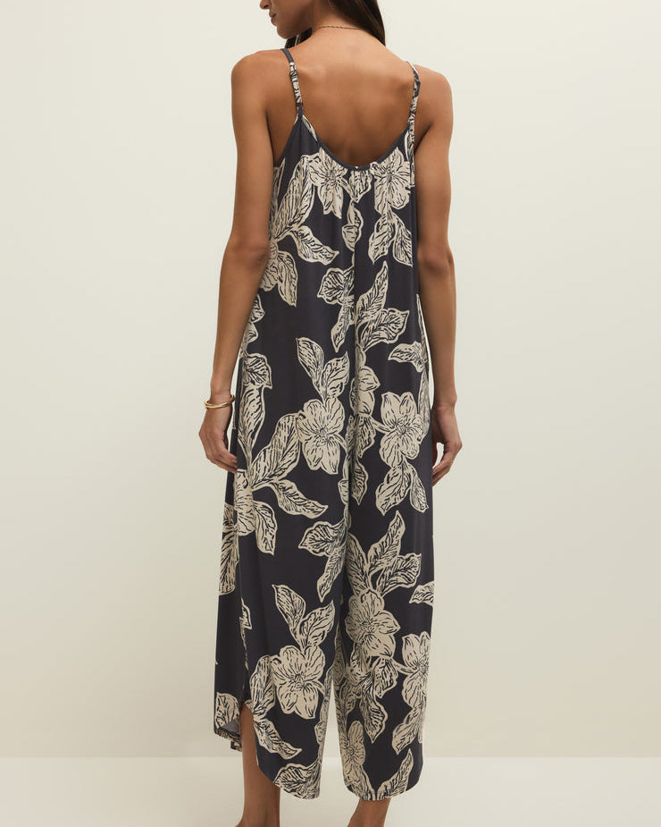 Woman wearing a floral jumpsuit on a plain background