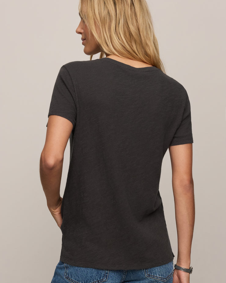 Person wearing a black t-shirt and blue jeans against a neutral background