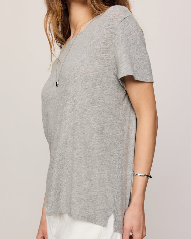 Person wearing a gray top and white pants on a plain background