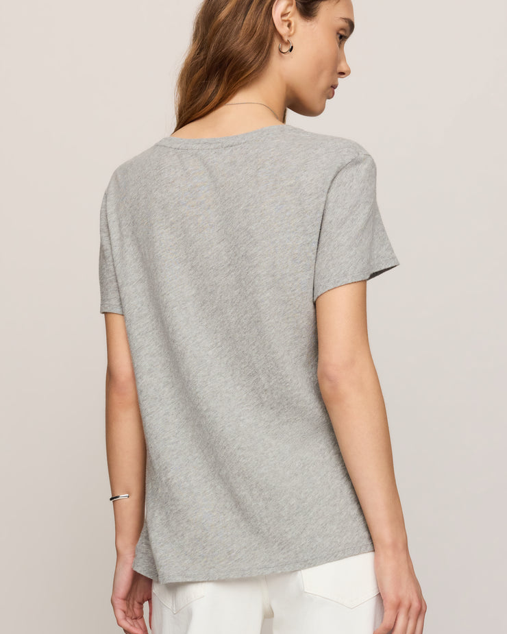 Woman wearing a gray t-shirt and white pants on a plain background