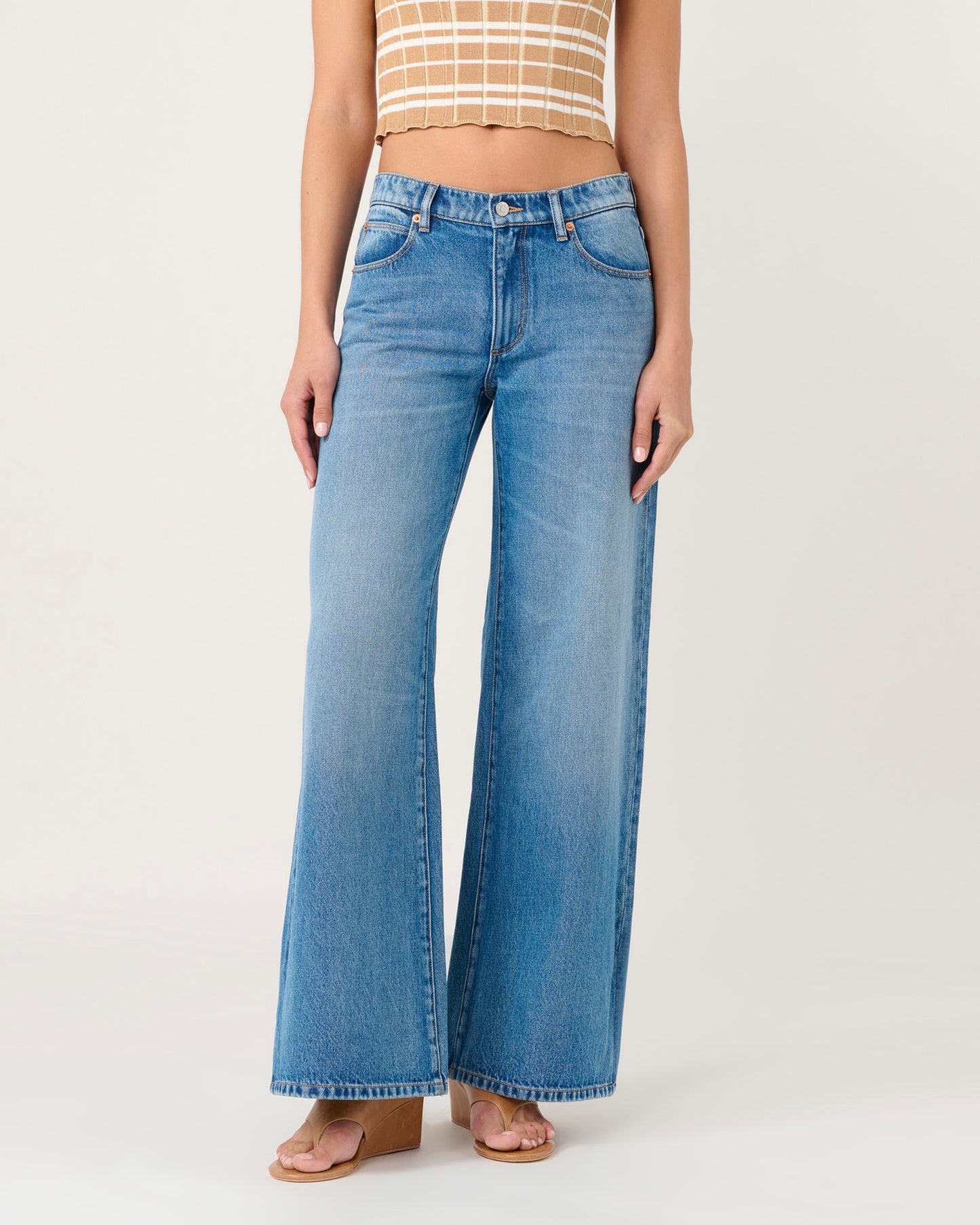 Person wearing blue flared jeans on a white background