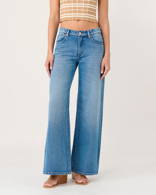 Person wearing blue flared jeans on a white background