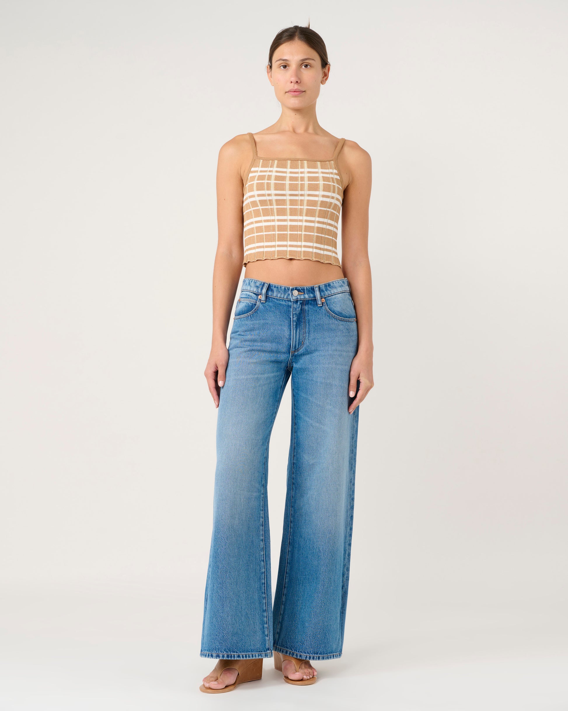 Woman wearing a checkered top and blue jeans on a white background