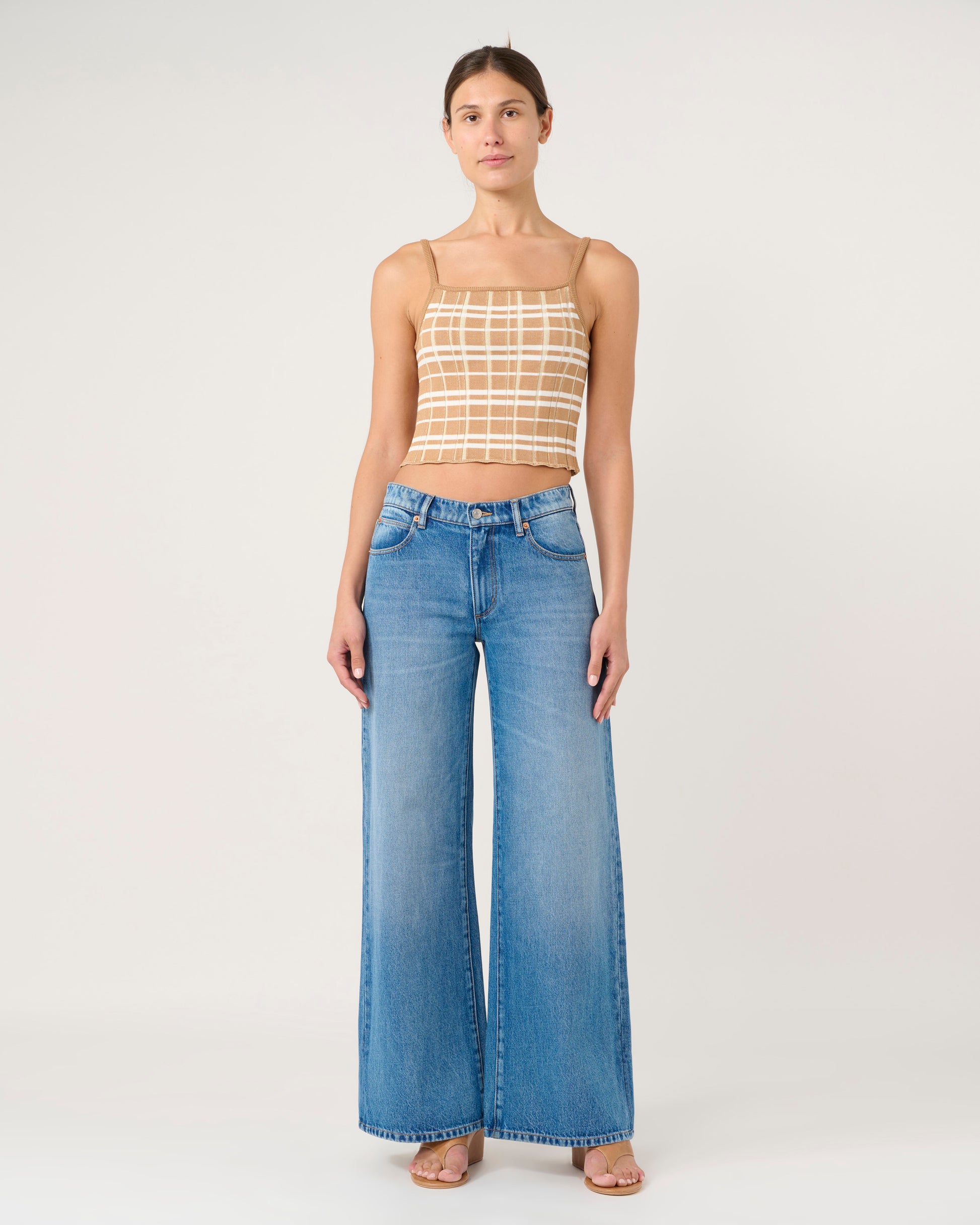 Woman wearing a checkered top and blue jeans on a white background