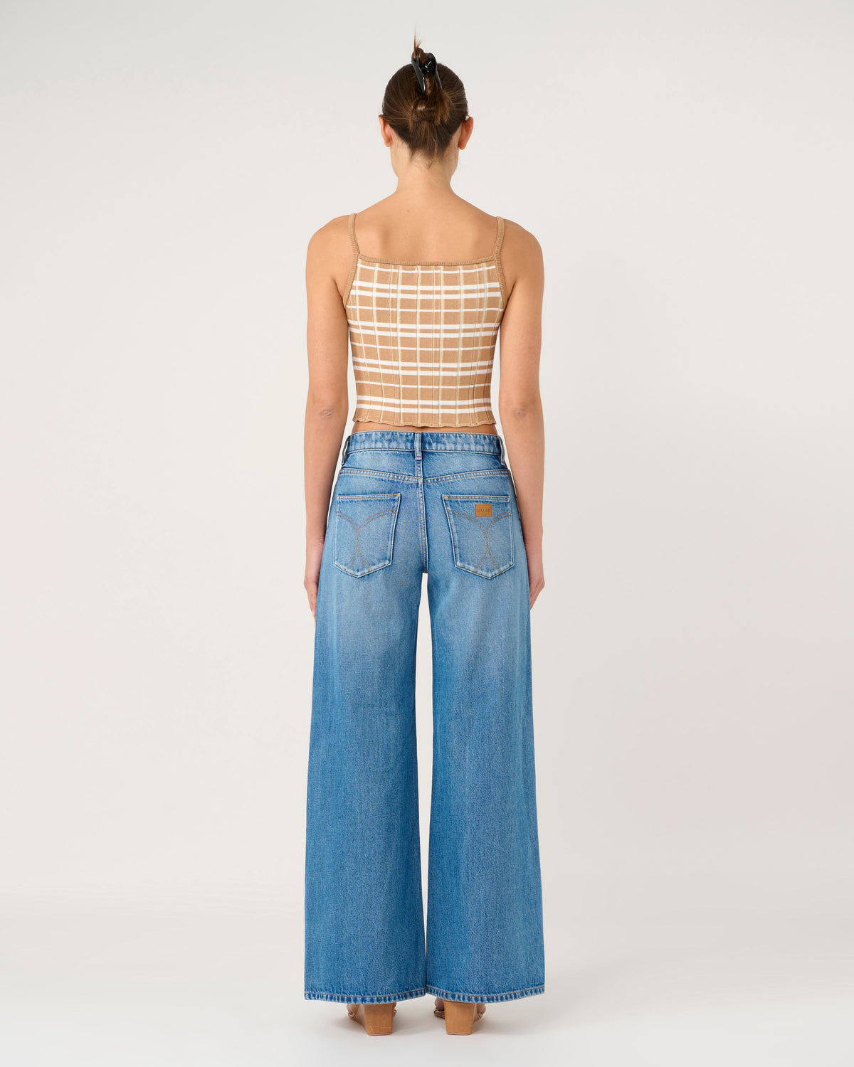 Person wearing a sheer top and blue jeans on a white background