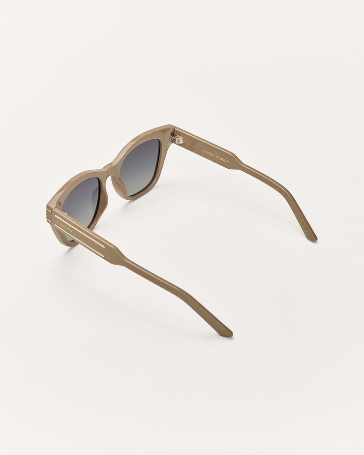 Sunglasses with a beige frame and dark lenses on a white background