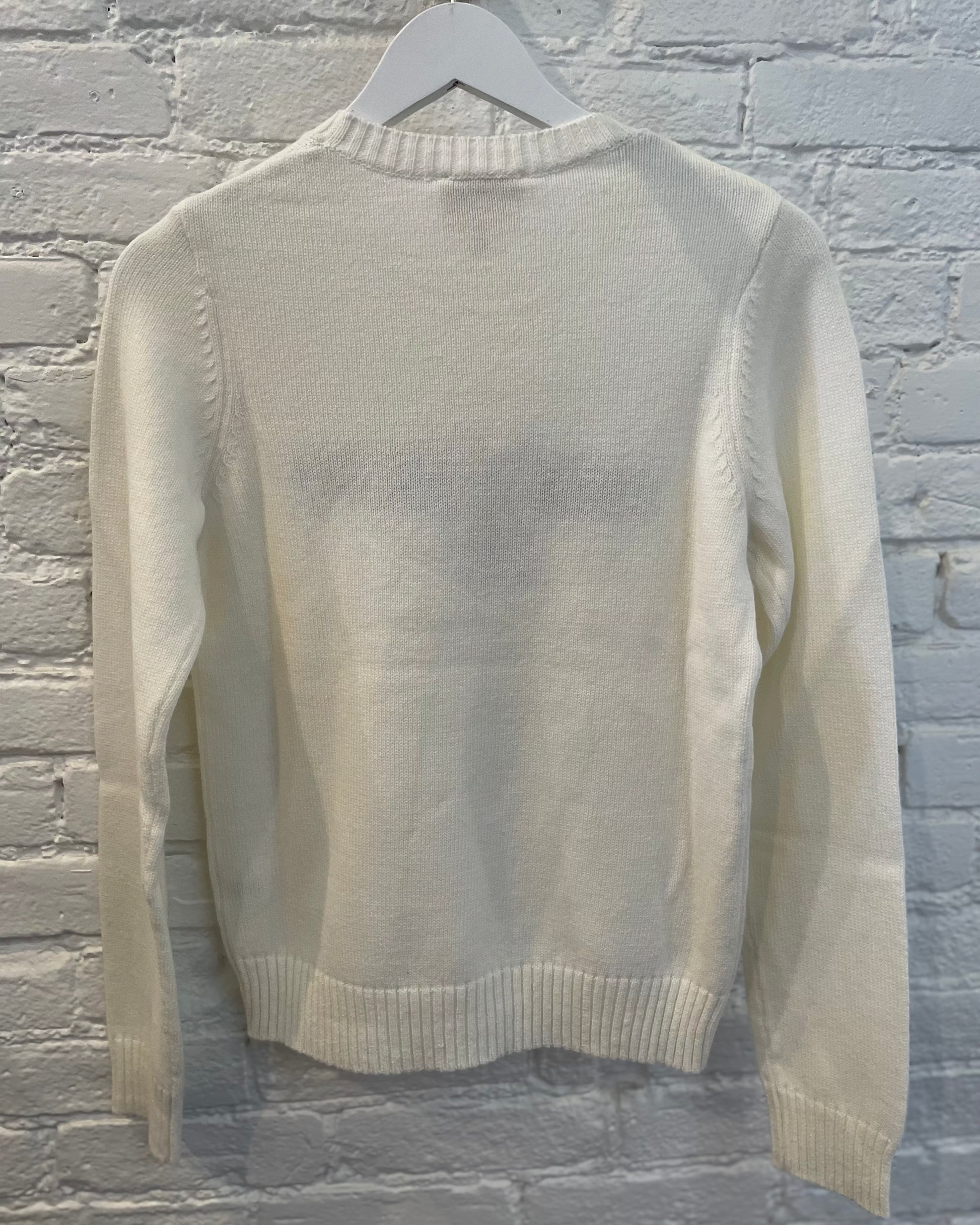 Beige sweater on a hanger against a gray brick wall