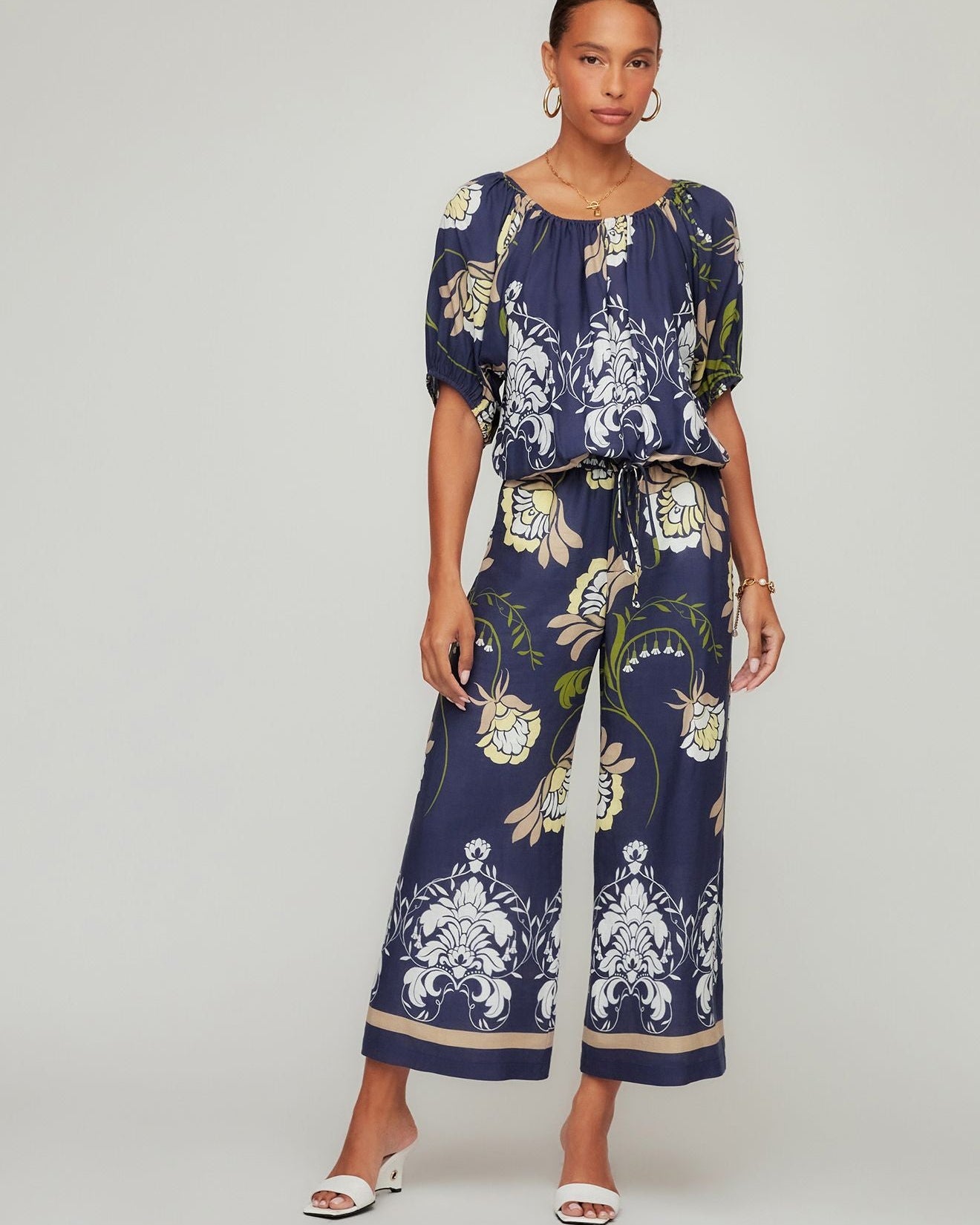 Woman wearing a navy floral jumpsuit on a white background