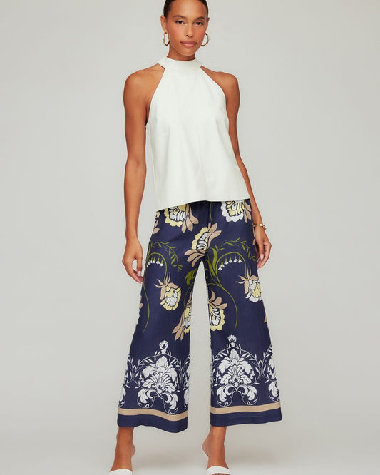 Woman wearing a white top and navy floral pants on a plain background