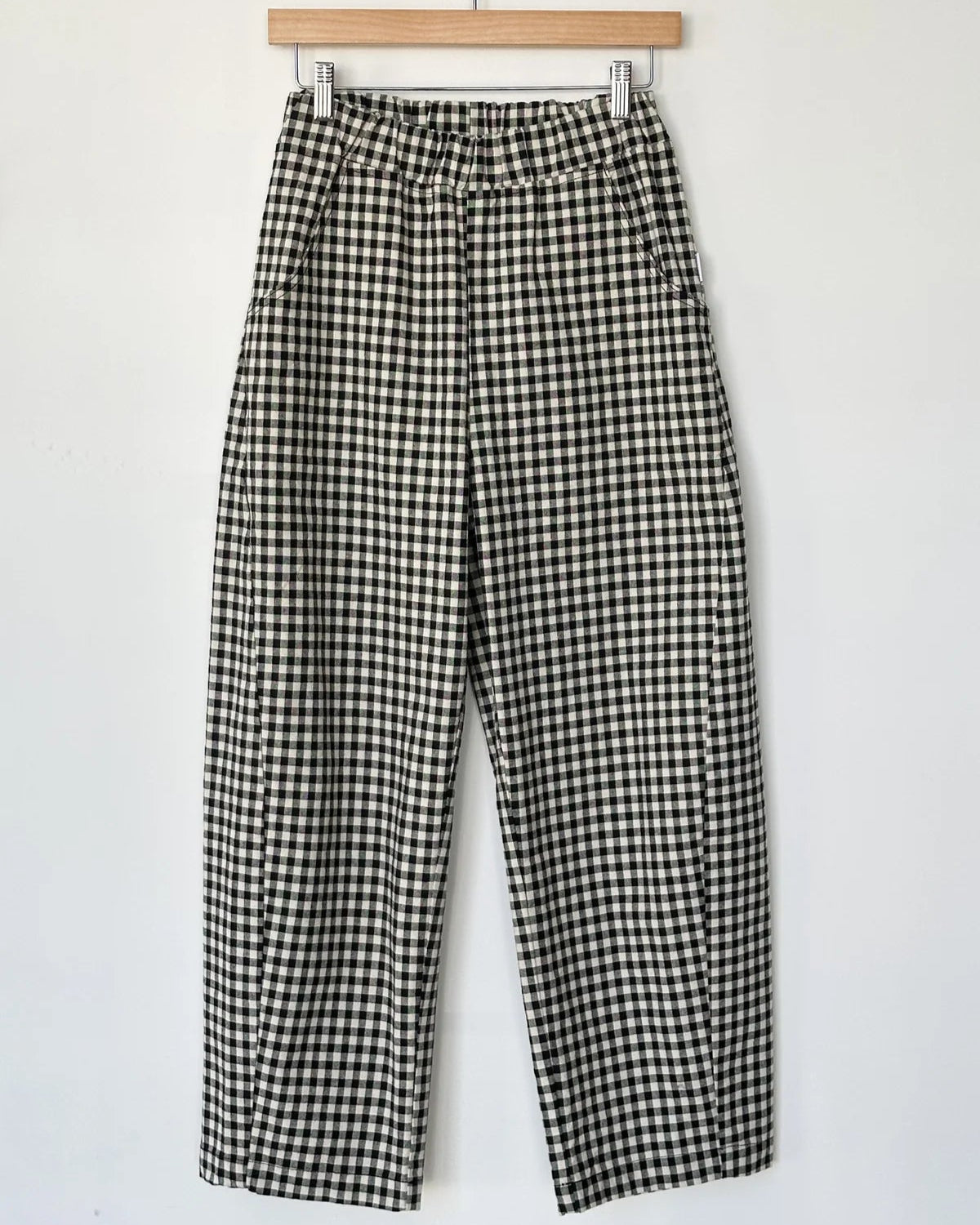 Black and white checkered pants on a hanger against a white background