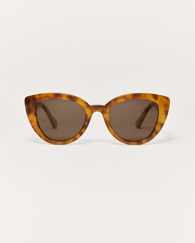 Tortoiseshell sunglasses with brown lenses on a light beige background
