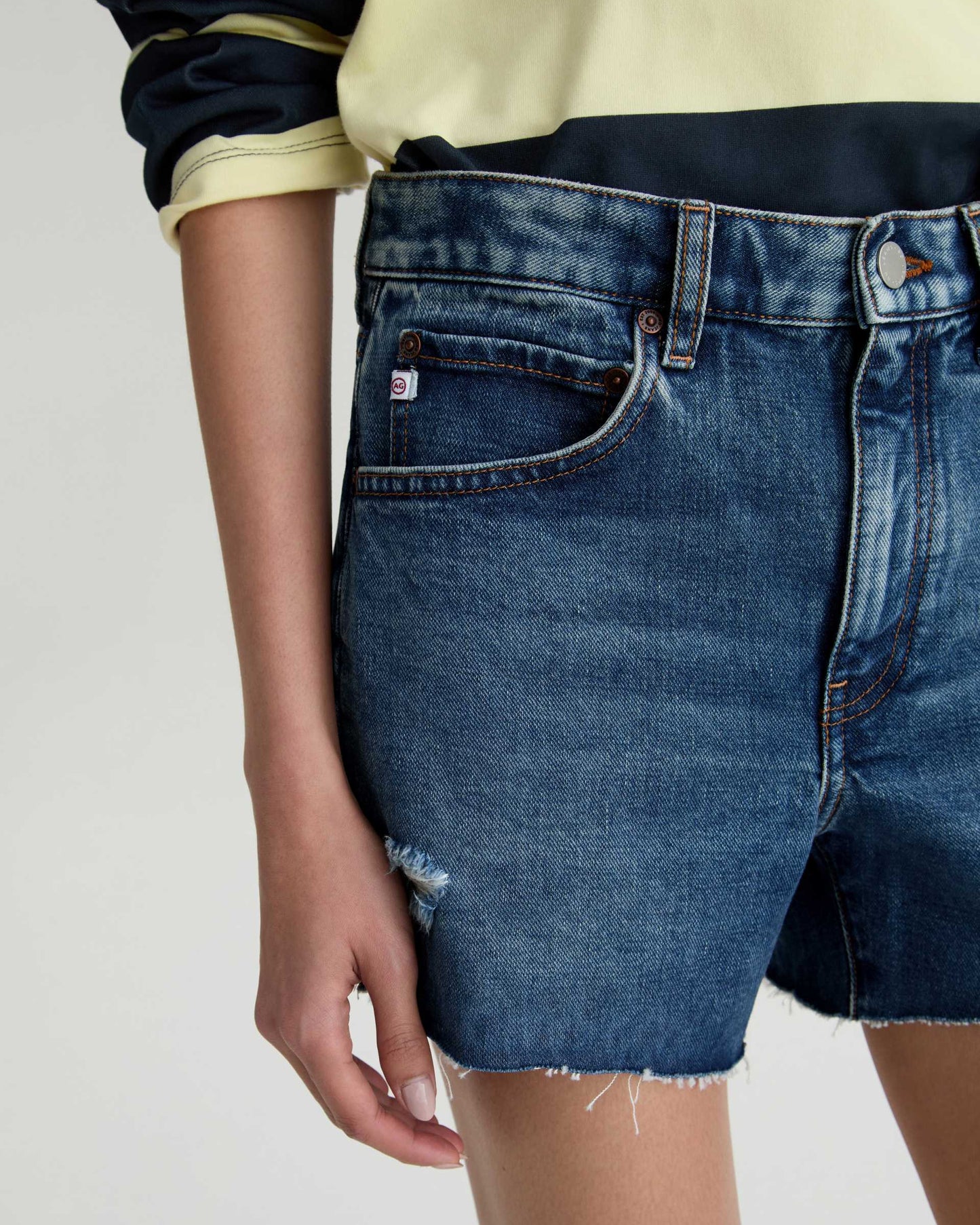 Person wearing blue denim shorts on a plain background